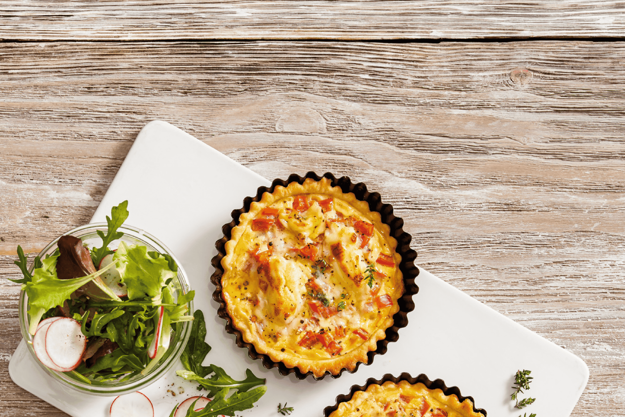 Quiche med salat på et træbord.