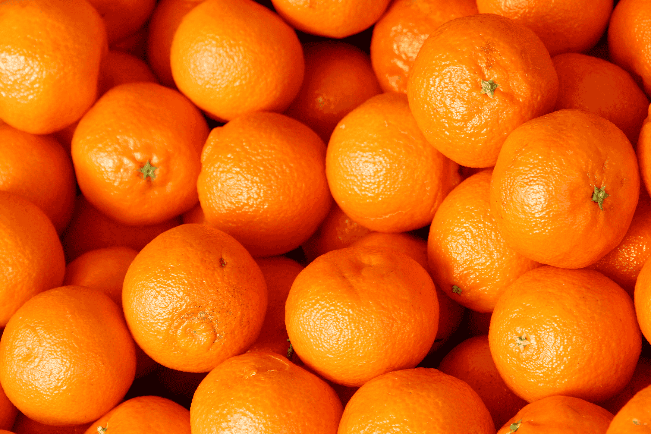 En bunke friske, lyse appelsiner med en ru tekstur på skallen.