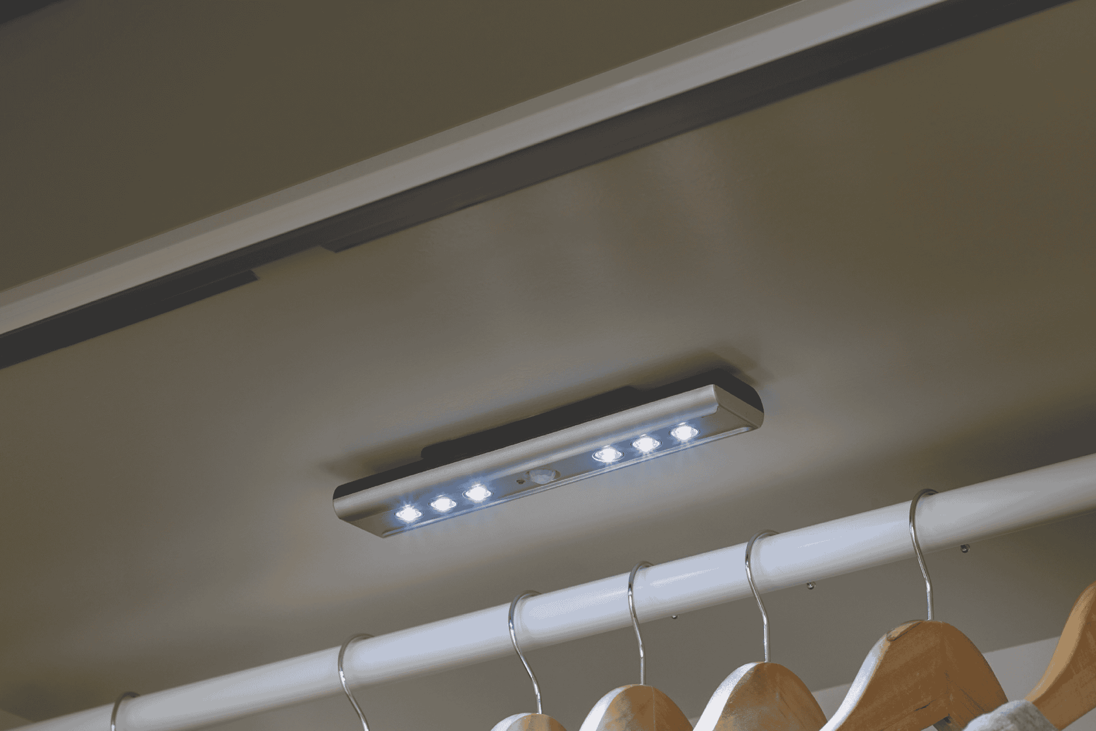 LED-skabslys med bevægelsessensor monteret i et skab over en tøjstang med bøjler.