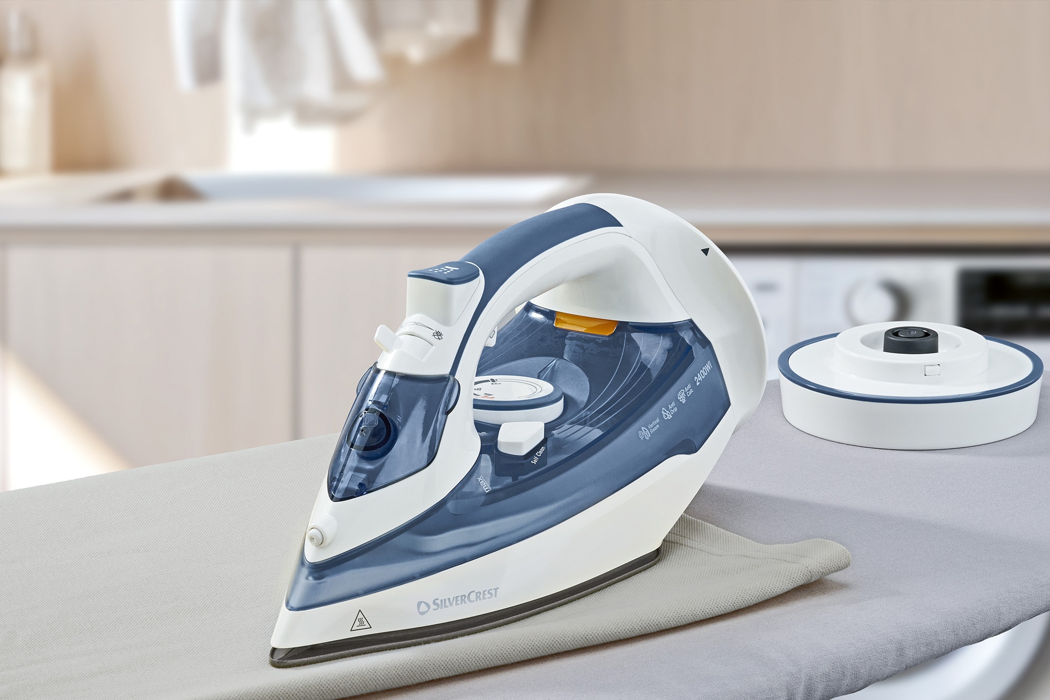 Dampstrygejern og vandbeholder på et strygebræt i et vaskerum.