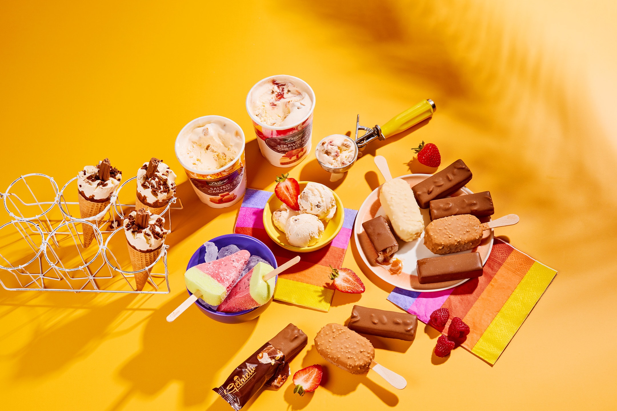 Et udvalg af is, ispinde og isvafler på en gul baggrund med skygger.