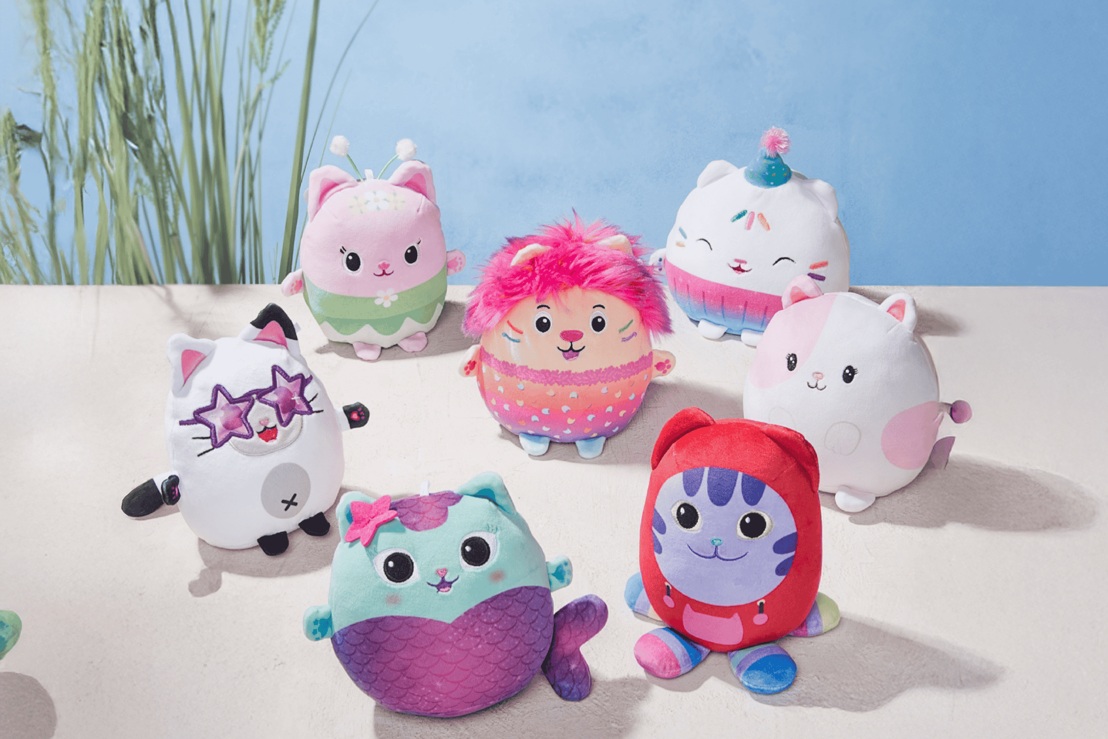 En samling af farverige Gabby's Dollhouse plyslegetøj, herunder havfrue-, fest- og løvekatte.