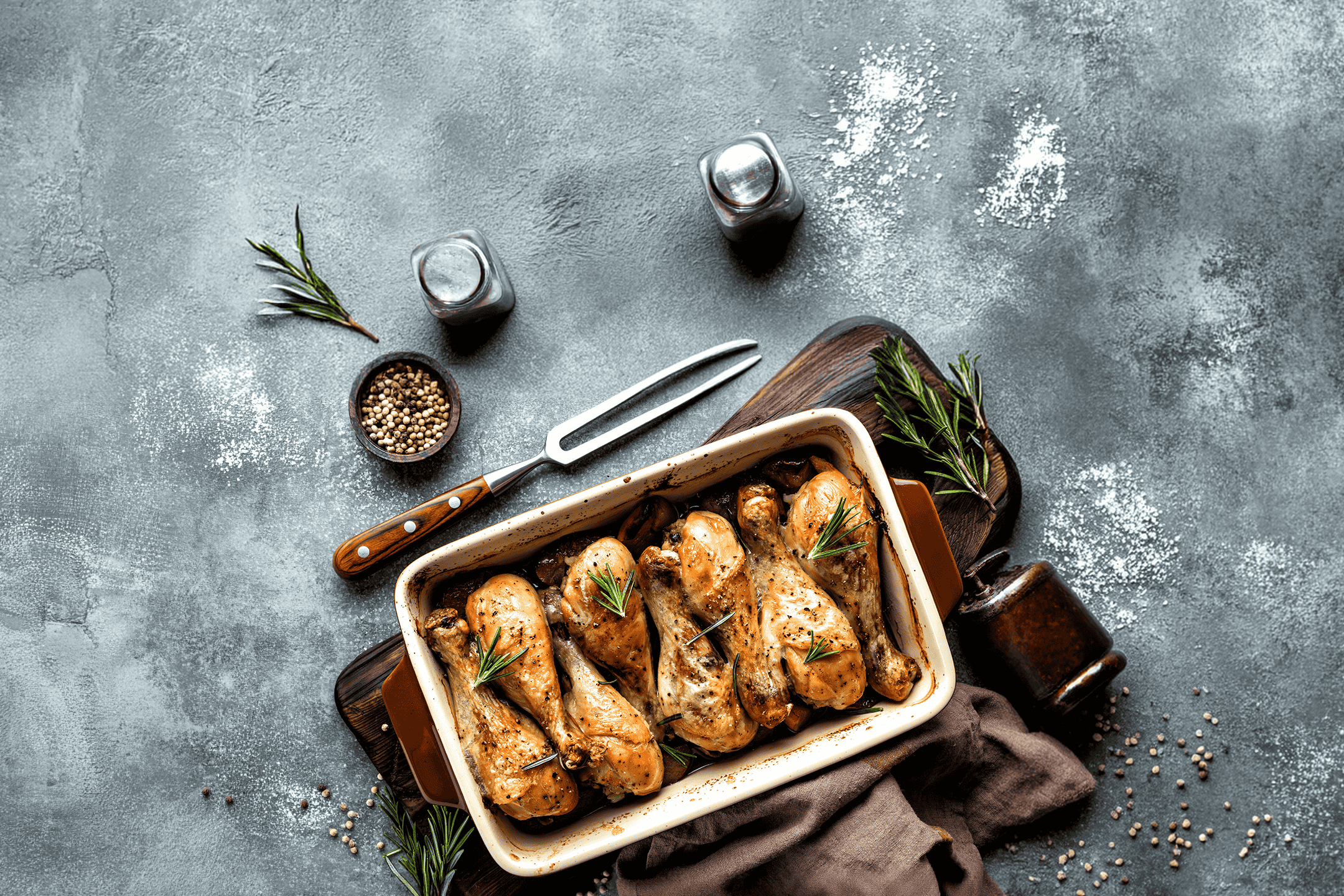 Ovnstegte kyllingelår med rosmarin i et fad på et rustikt bord.