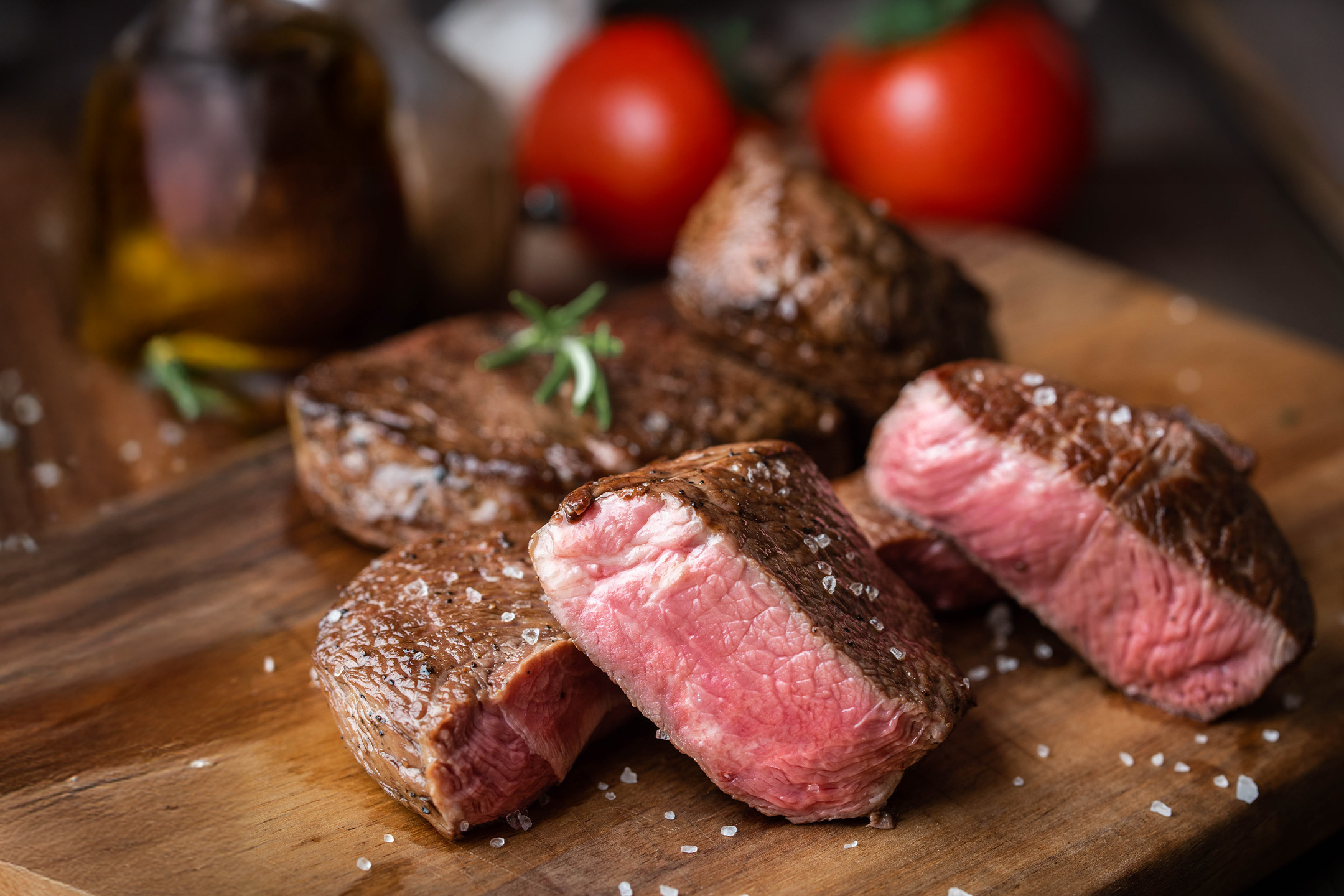 Skåret oksekød med rosmarin og havsalt på et træskærebræt.