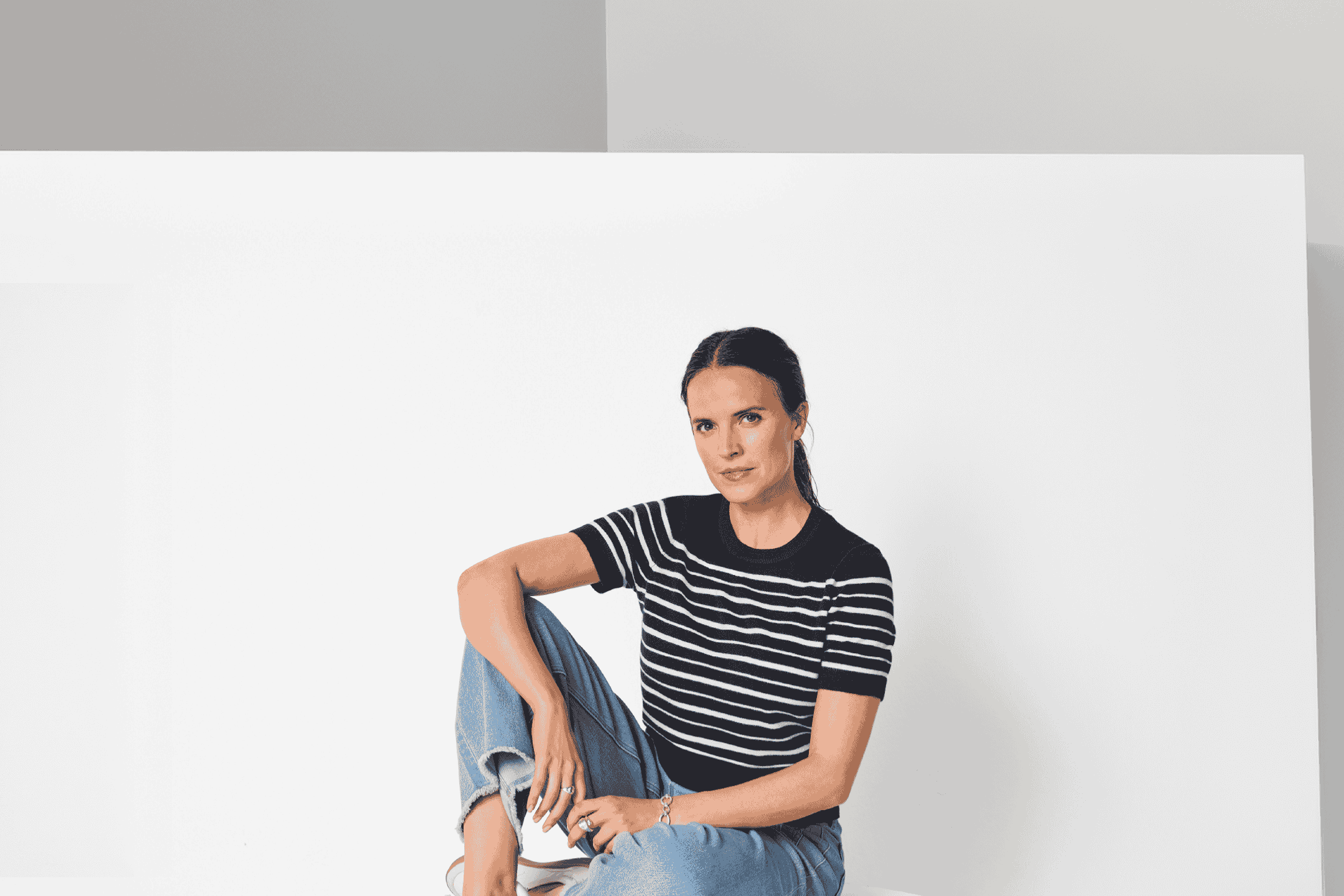 Kvinde i stribet T-shirt og jeans sidder på gulvet.