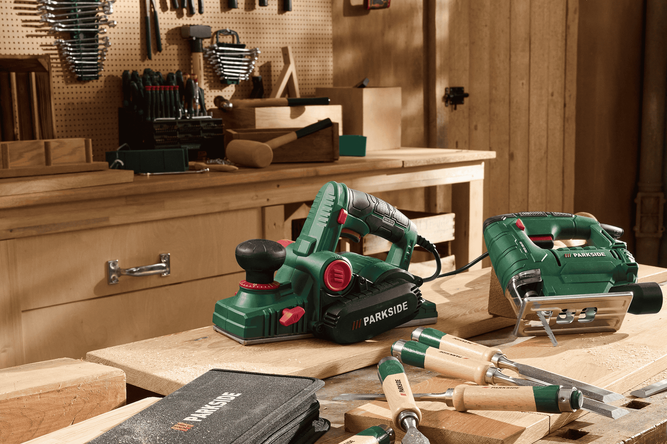 En elektrisk høvl og en stiksav på et træværksted med træbearbejdningsværktøj.