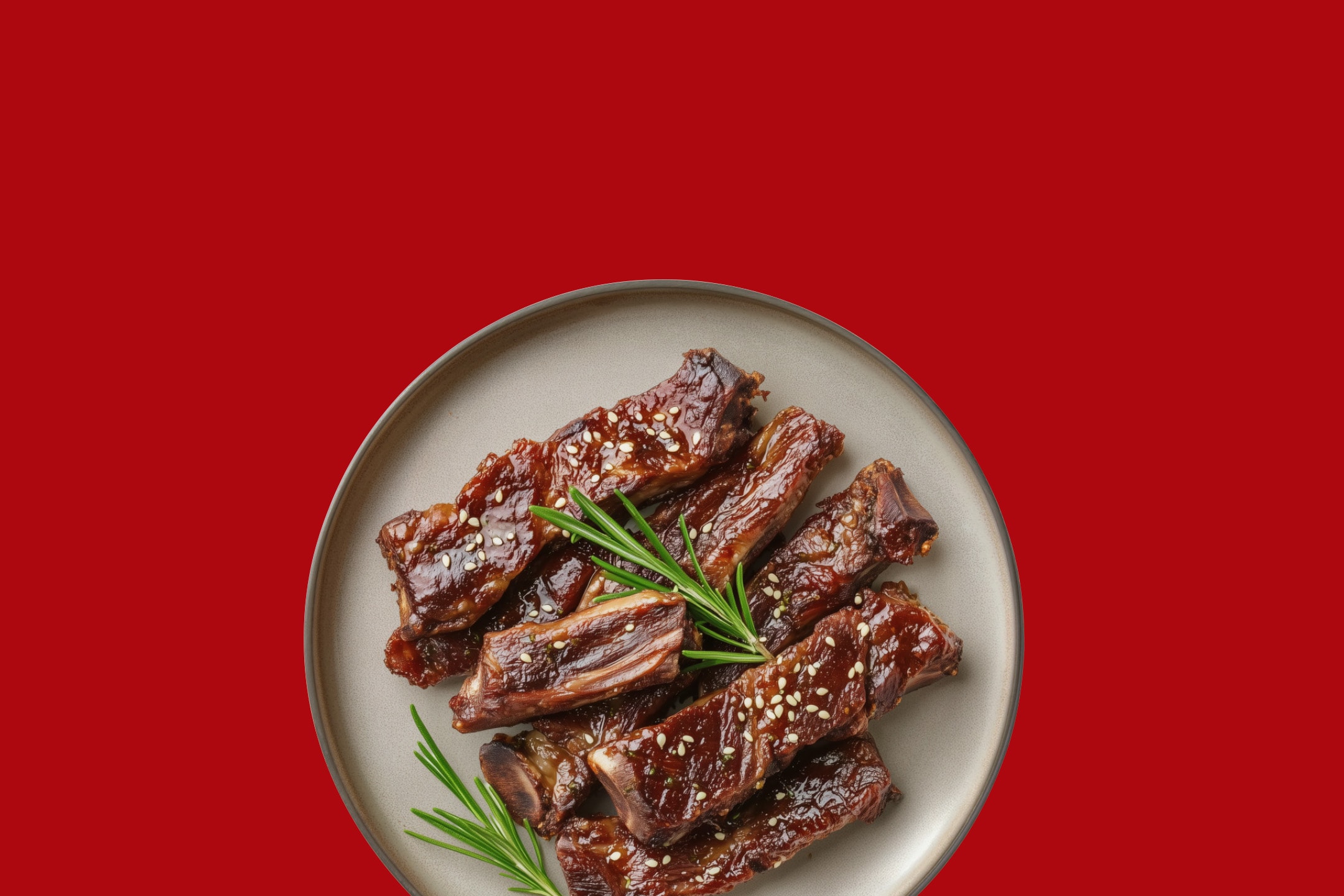 Glaserede spareribs med sesamfrø og rosmarin på en tallerken.
