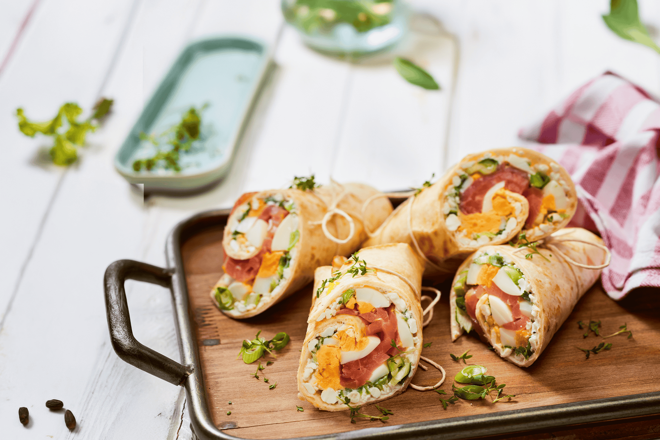 Tortilla-wraps med æg, skinke og grøntsager på et træfad.