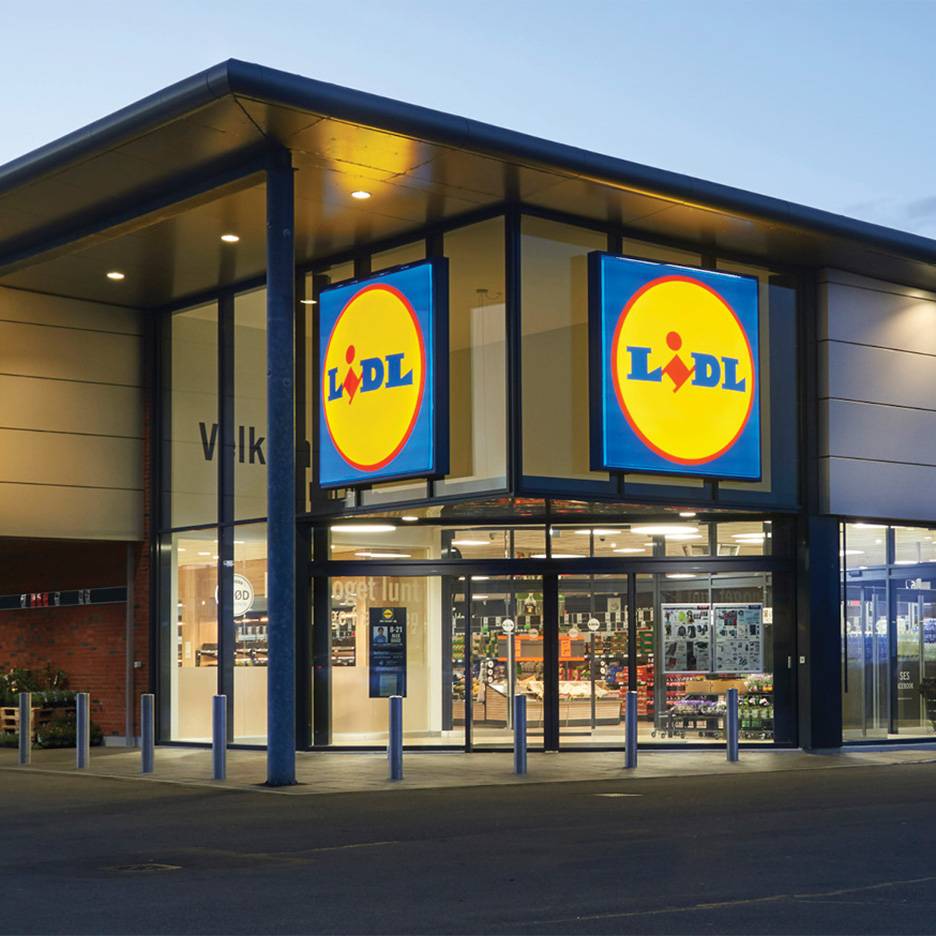 Lidl butiksfacade om aftenen med oplyste skilte og indgangsparti.