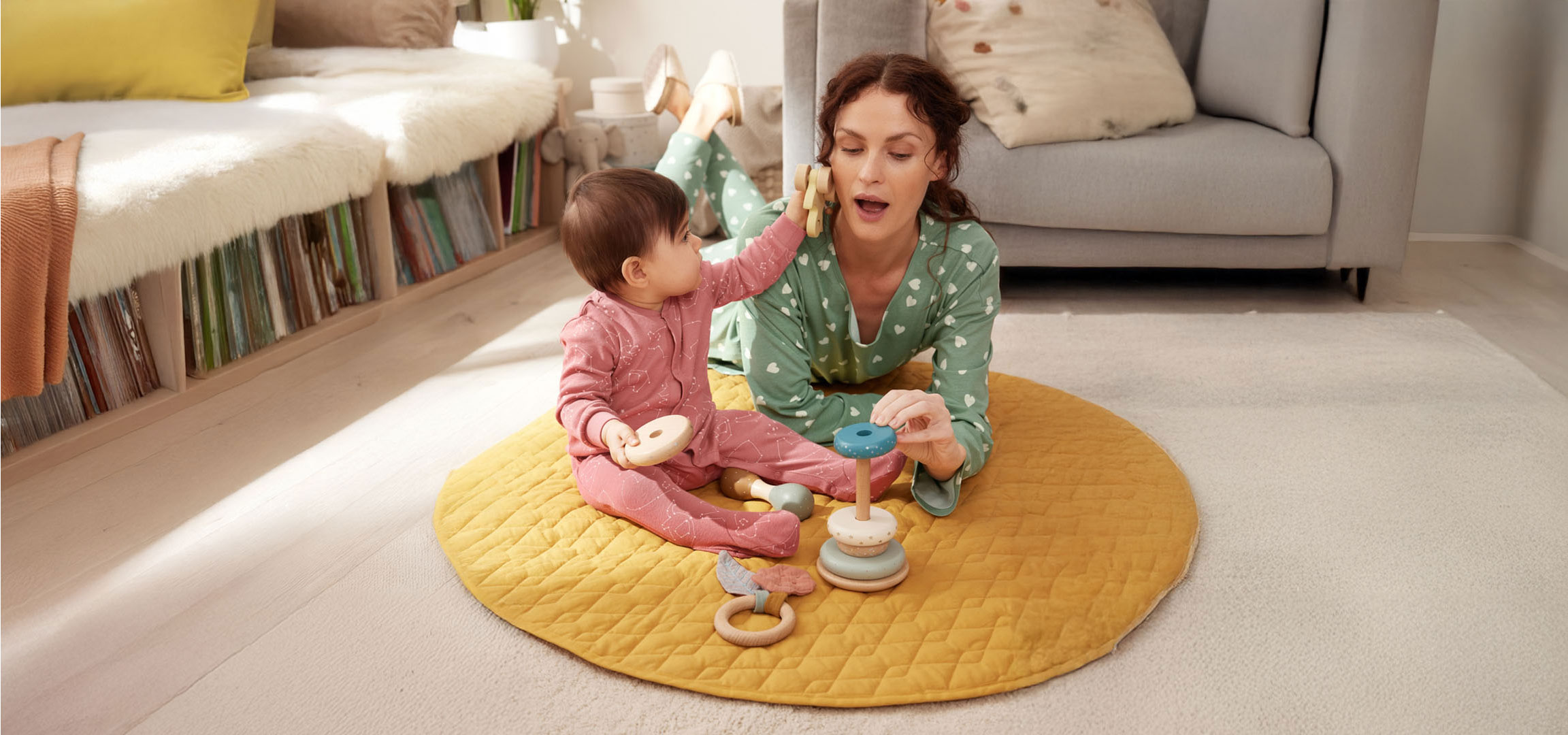 Mor og baby leger med legetøj på gulvet.