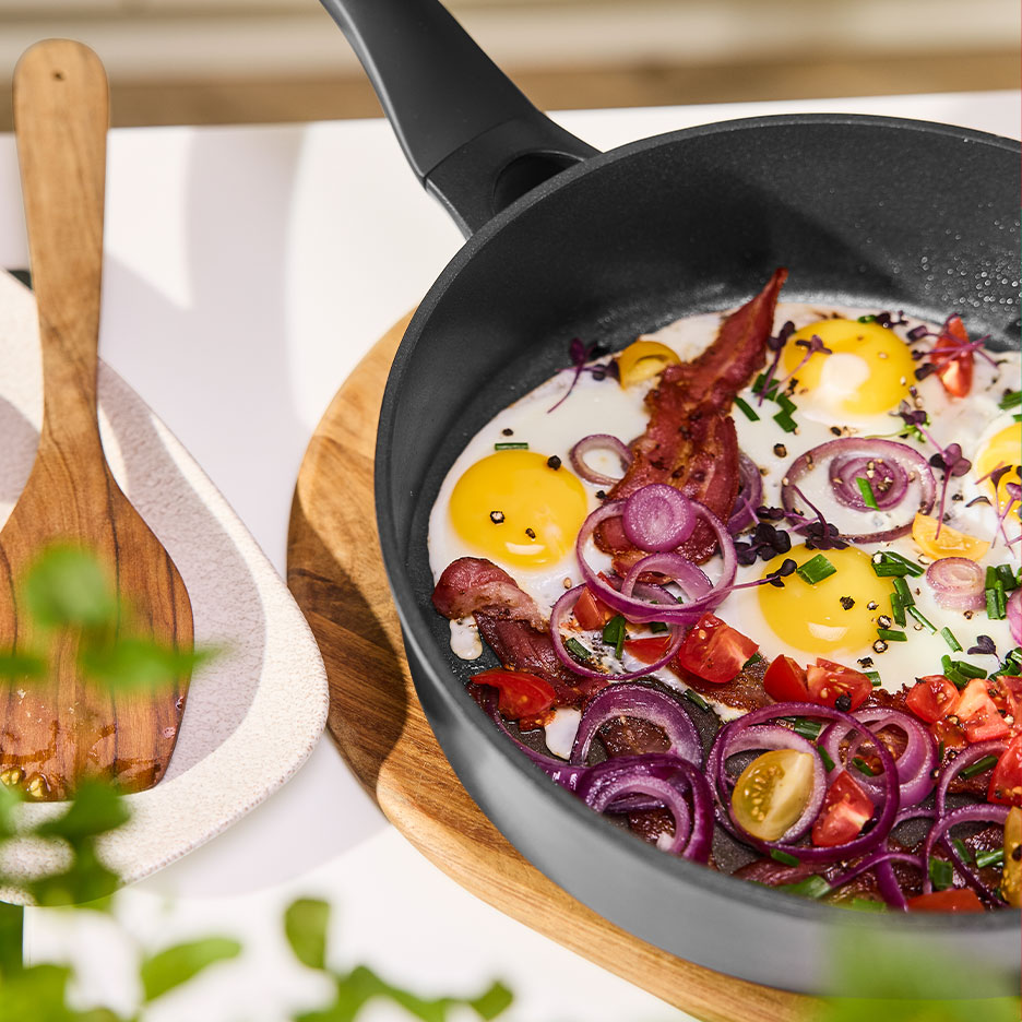 Stegepande med spejlæg, bacon, rødløg og tomater.