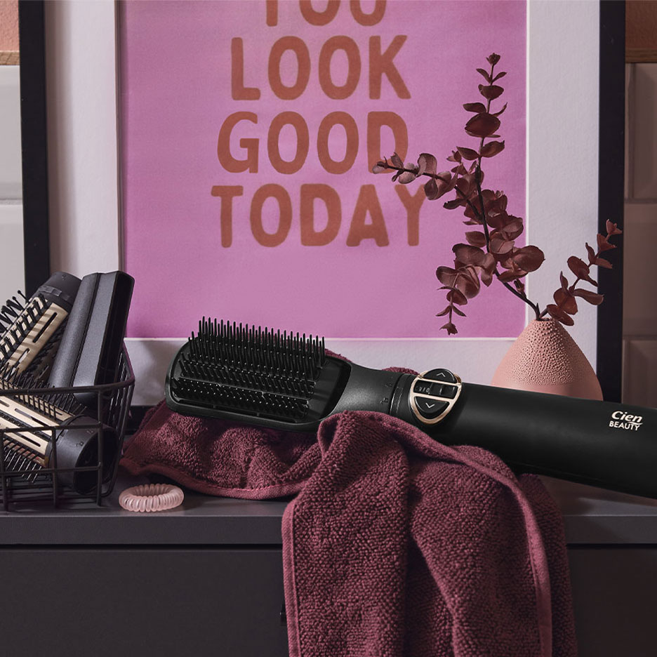 Cien Beauty glattebørste på et håndklæde, med hårtilbehør og en plakat.