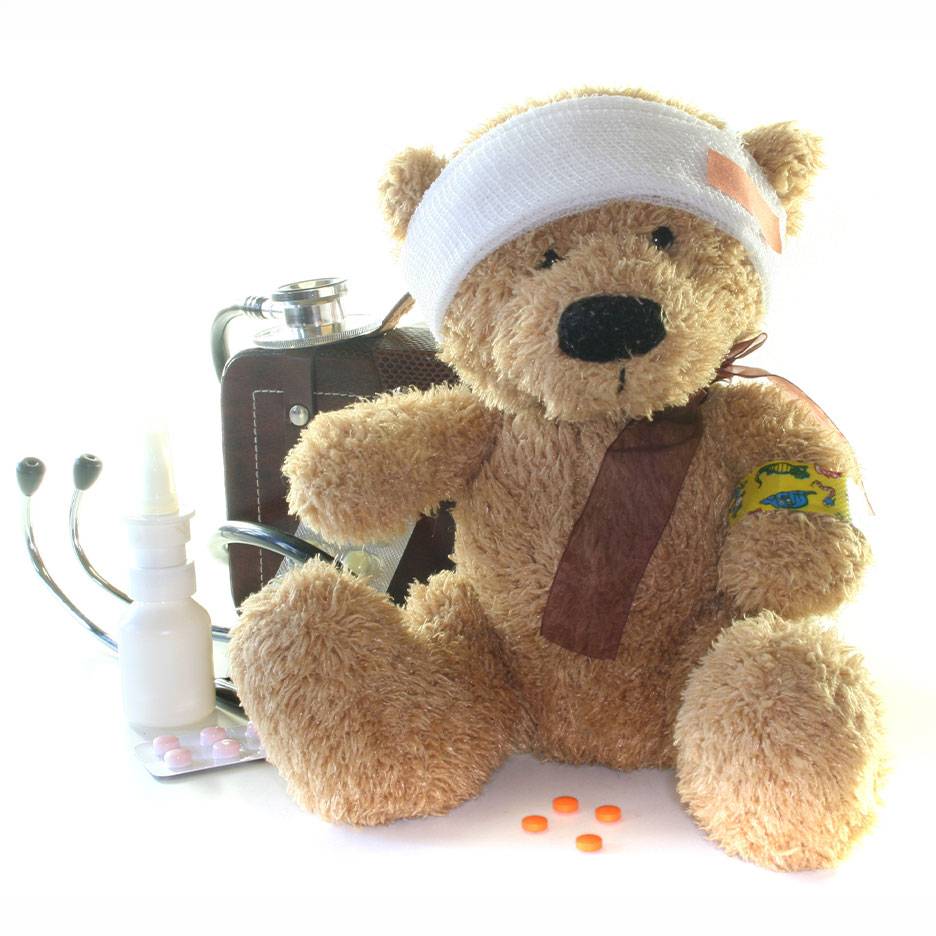Skadet bamse med hovedforbinding, lægetaske, stetoskop og medicin.