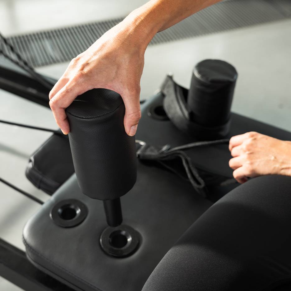 Person justerer en sort polstret træningsmaskine.