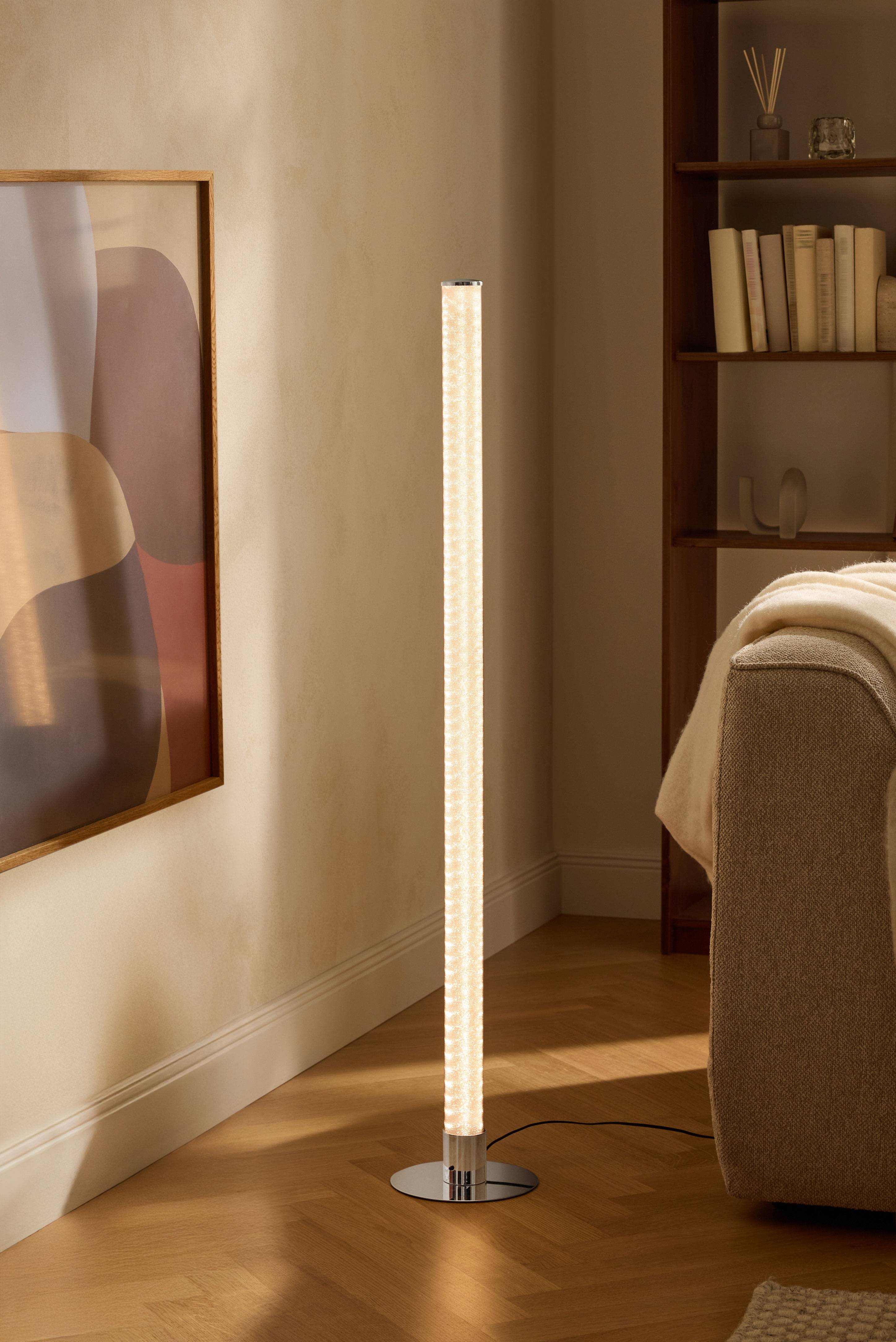 Moderne gulvlampe i stue med bogreol og sofa.