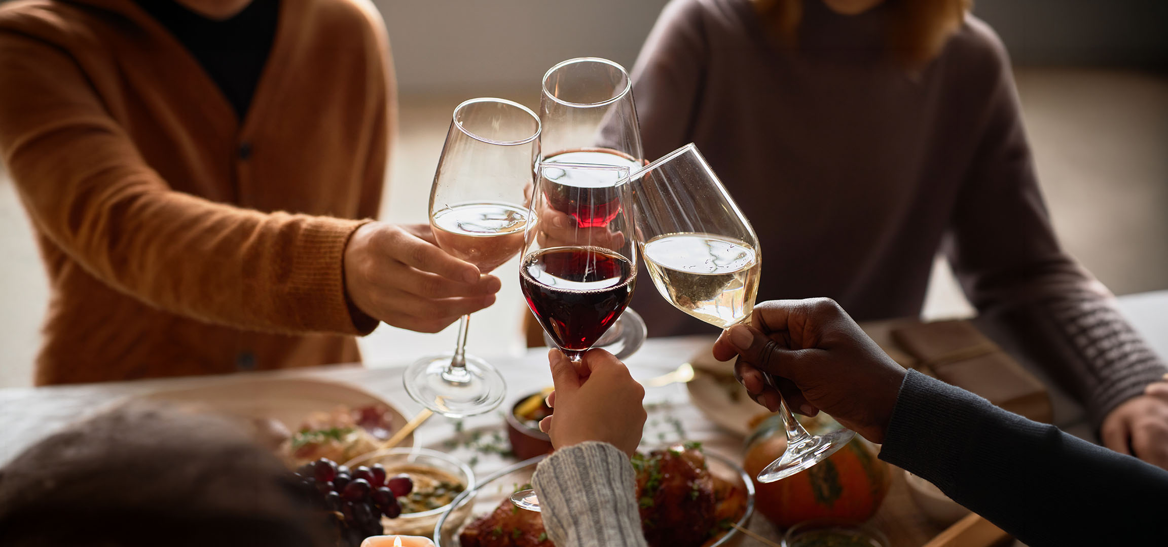 Folk skåler med glas med rød- og hvidvin.