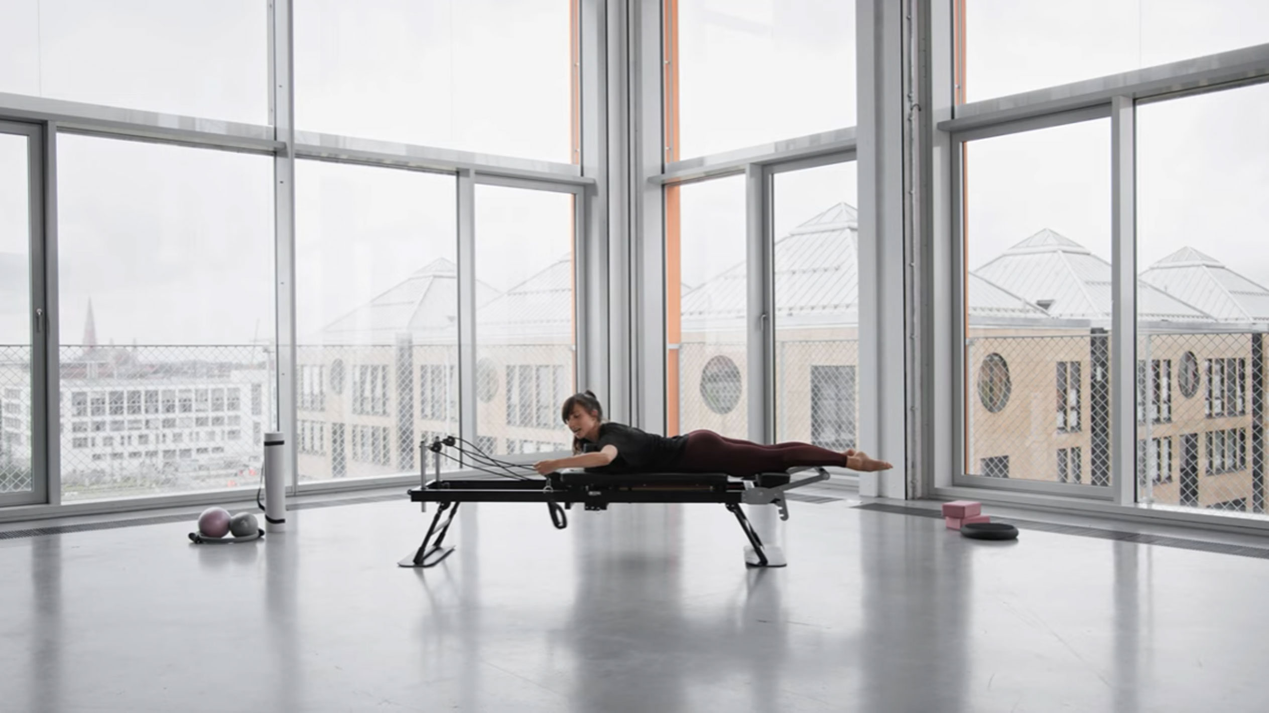 Kvinde laver Pilates på en reformer med udsigt over byen.