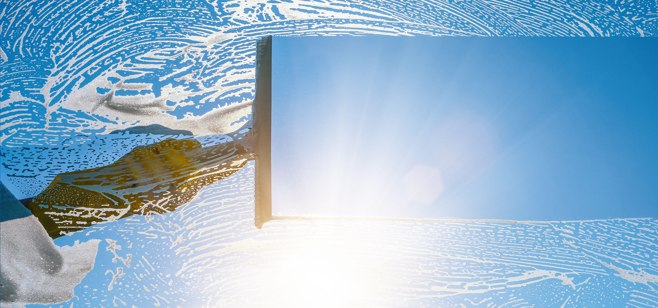 Vinduespudsning med sæbeskum på en blå himmel.