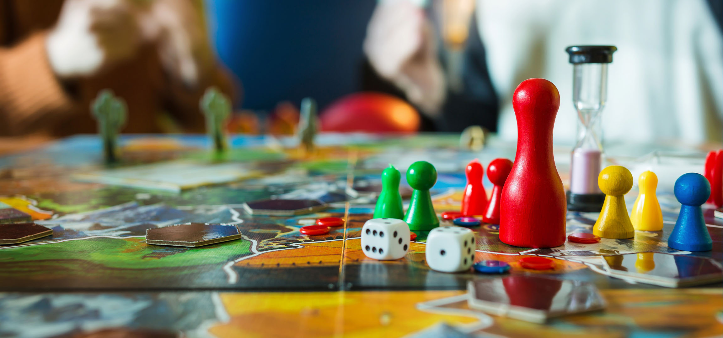 Farverige brætspilsbrikker, inklusive røde, grønne, gule og blå brikker, med terninger.