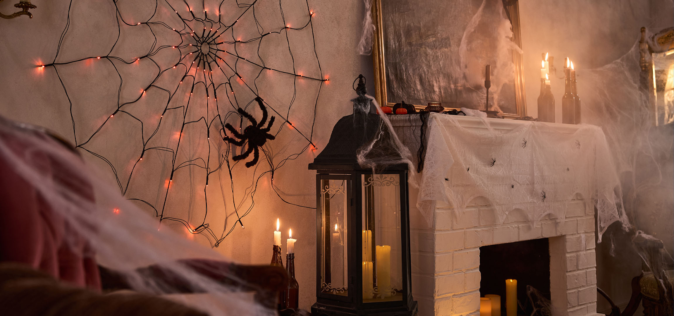 Halloween-dekorationer med spindelvævslys, en stor edderkop og stearinlys.