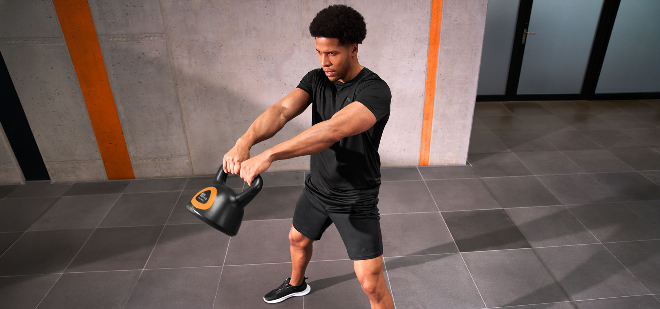 aiLabeling.aiLabelForImageAltText: Mand der træner med en sort og orange kettlebell.