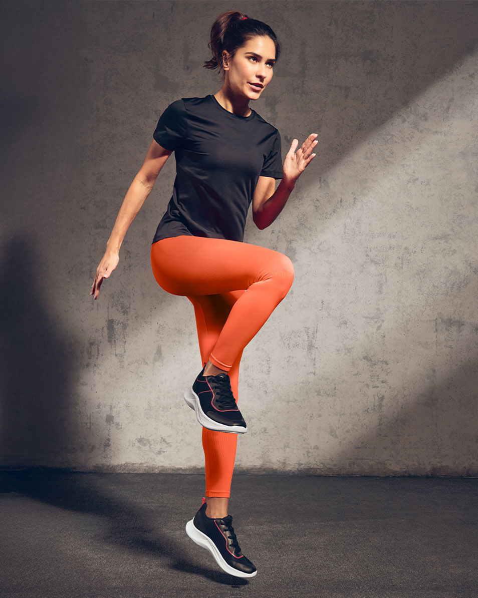 Kvinde i sort sportst-shirt og orange leggings træner