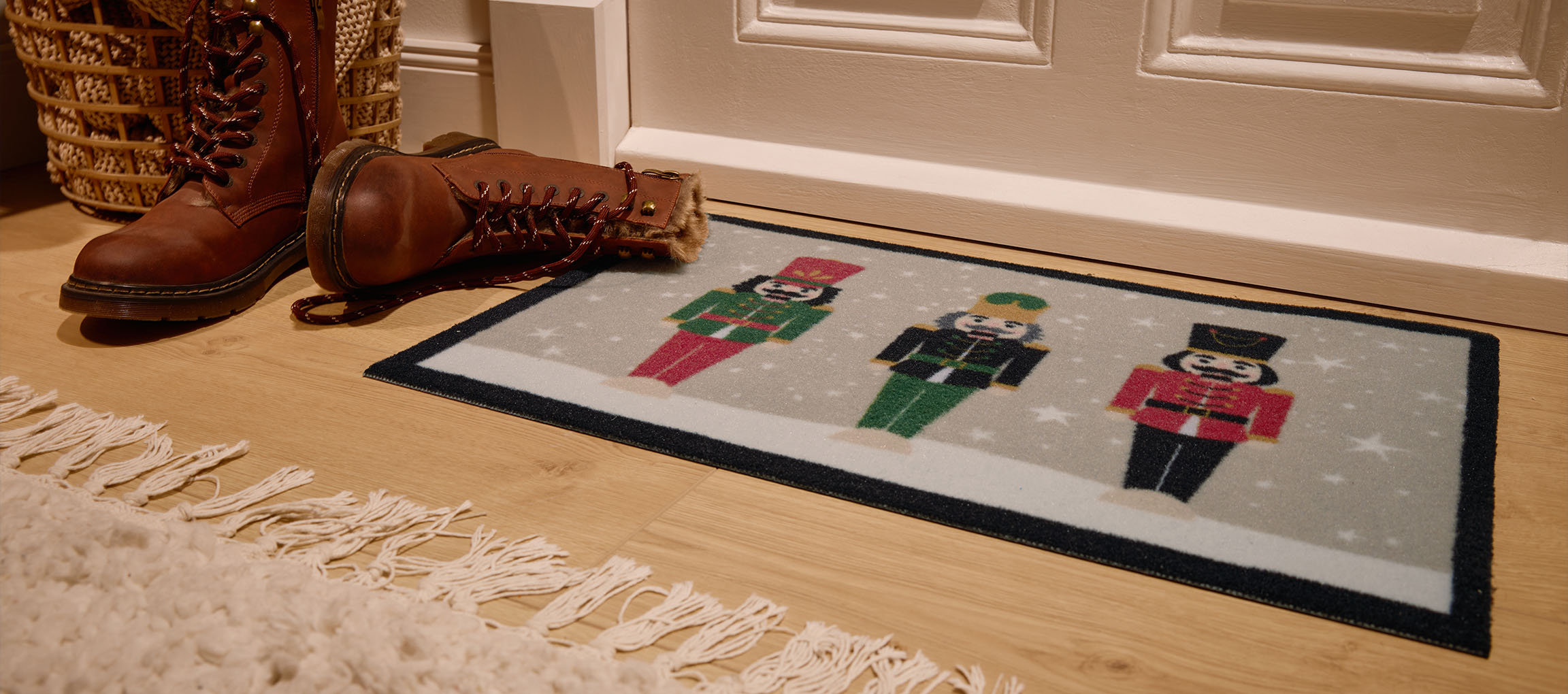 Julemåtte med nøddeknækkere, brune støvler og fletkurv ved indgangen.