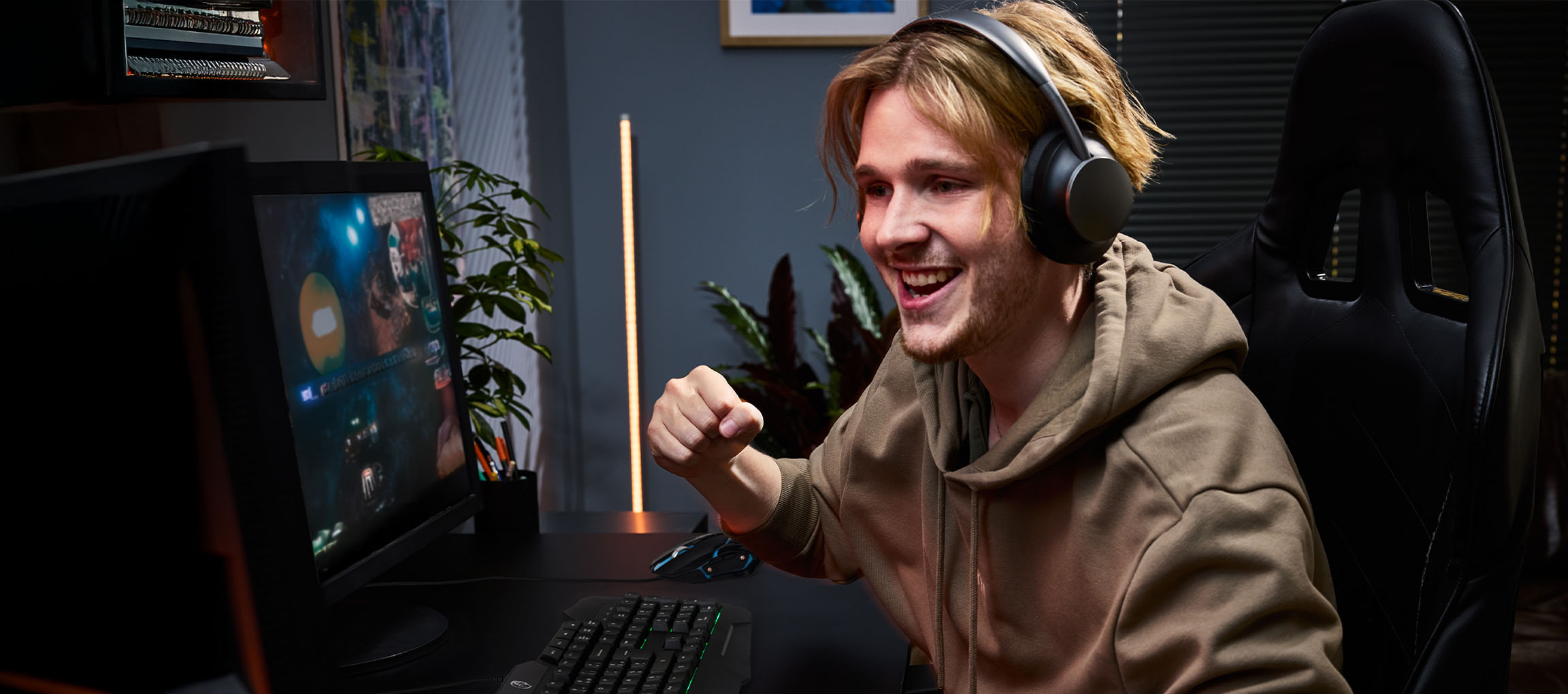 Ung mand med hovedtelefoner spiller videospil med gaming tastatur og mus