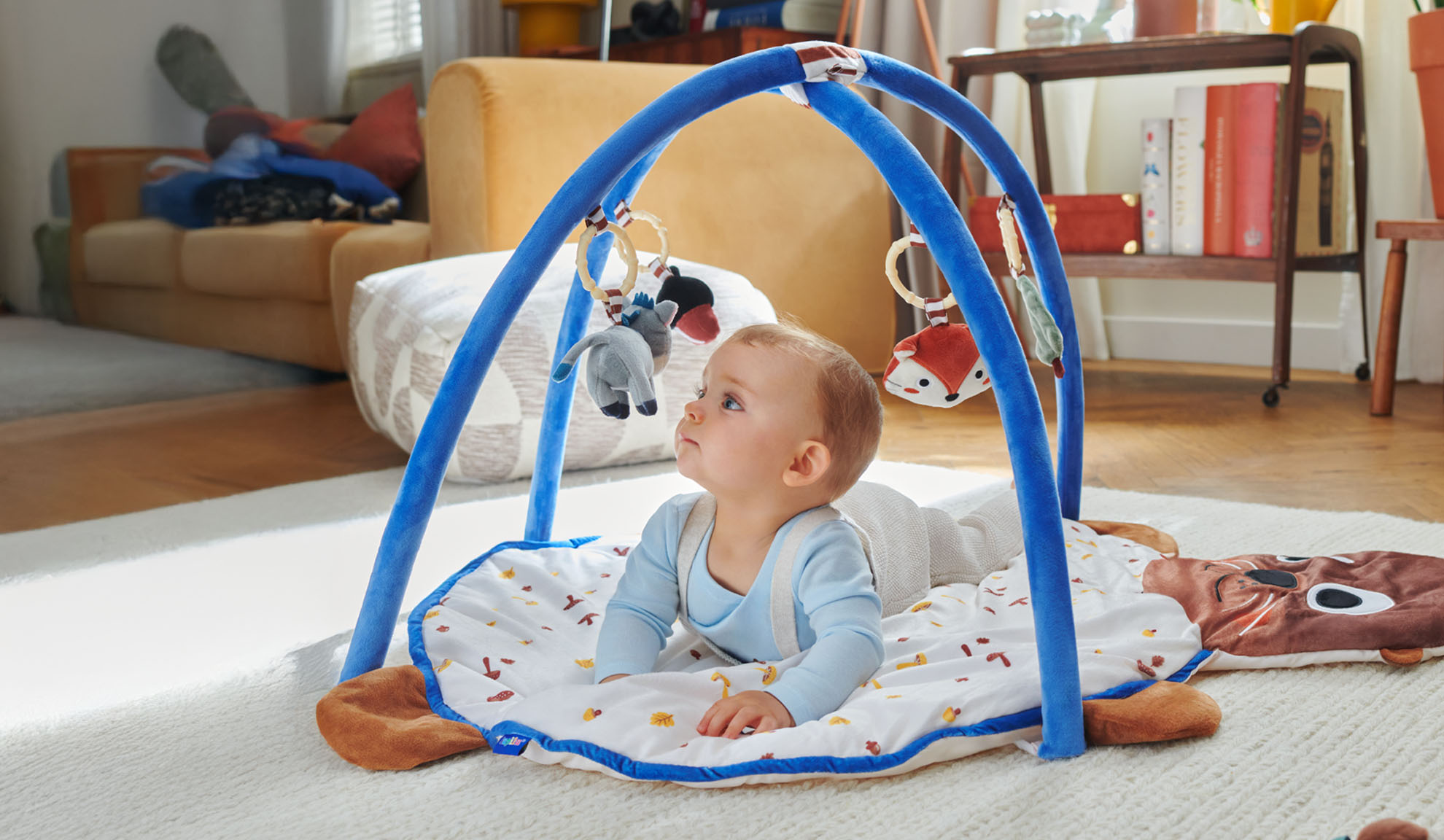 En baby leger på en Tiny Love aktivitetsmåtte med en bue i form af dyr.