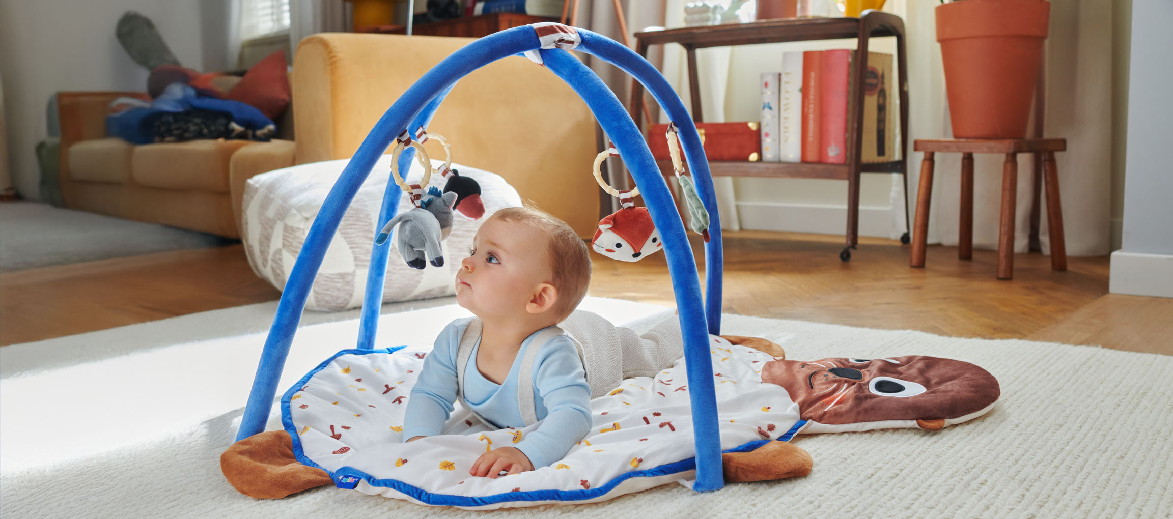 En baby leger med et Little Dutch legetæppe formet som en sæl.