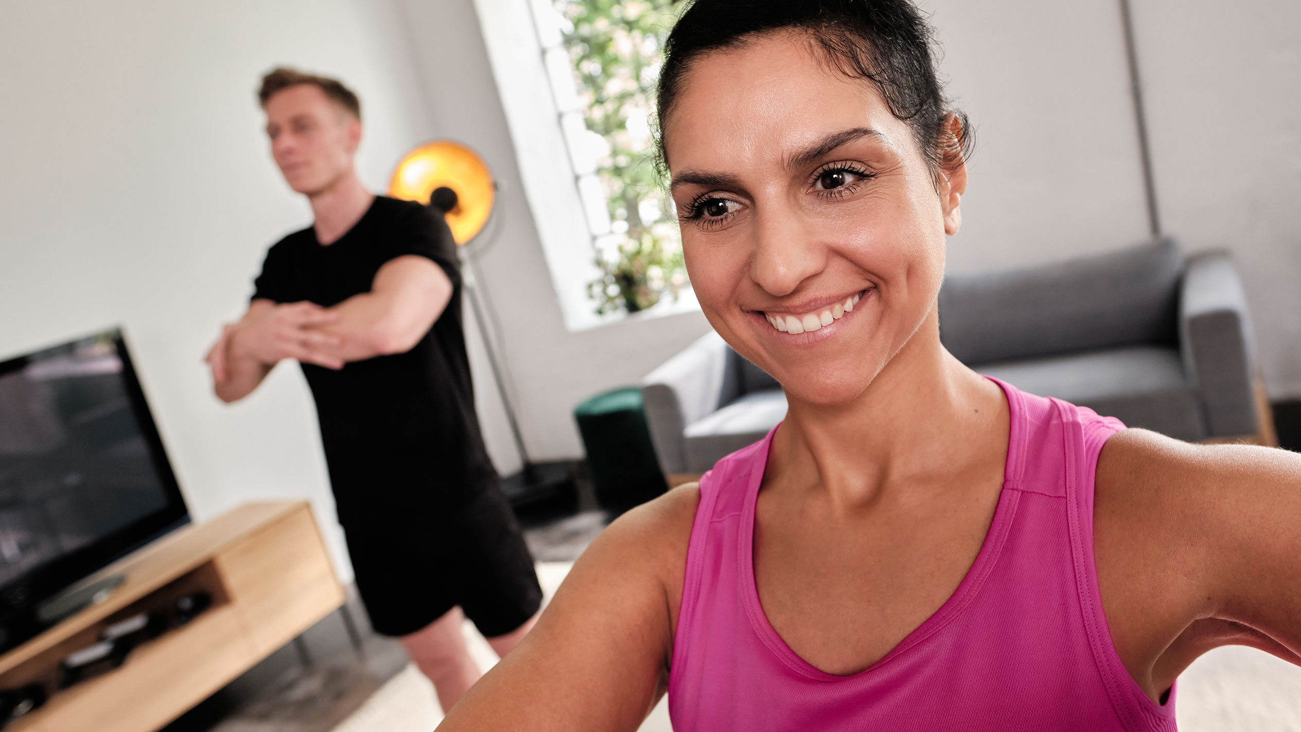 Smilende kvinde, der træner hjemme med sin partner.