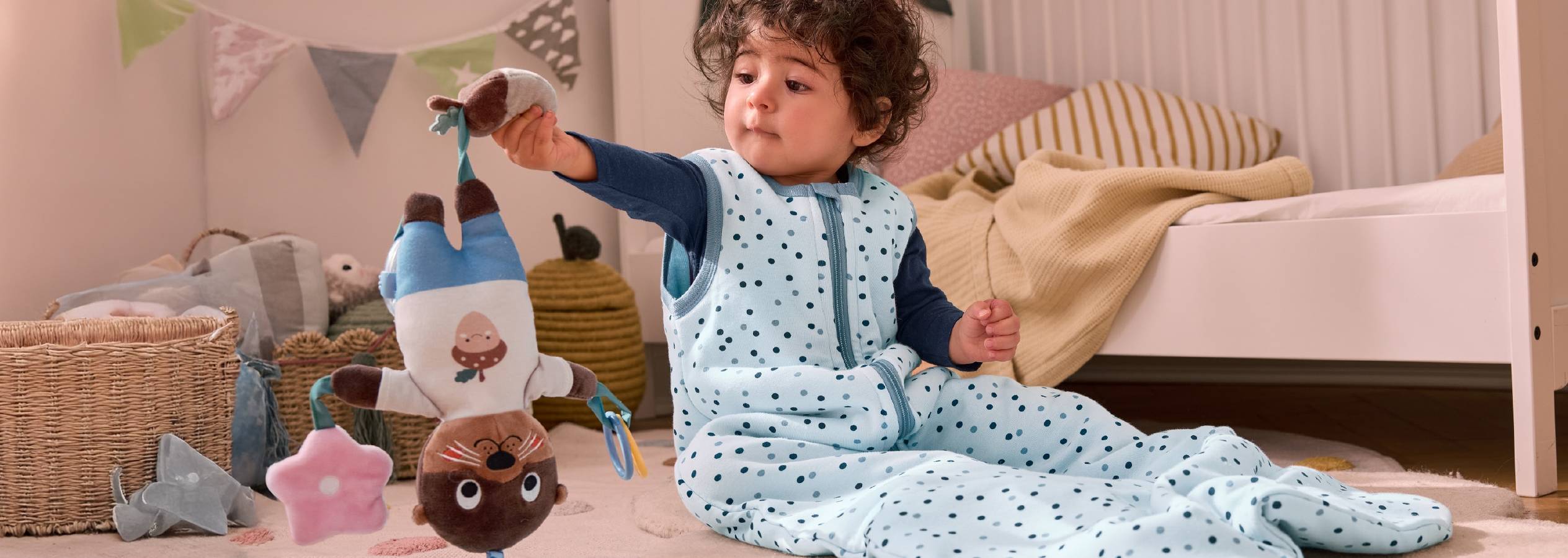 Et barn i en SleepBag fra aden + anais leger med en nuttet legetøjs-odder.