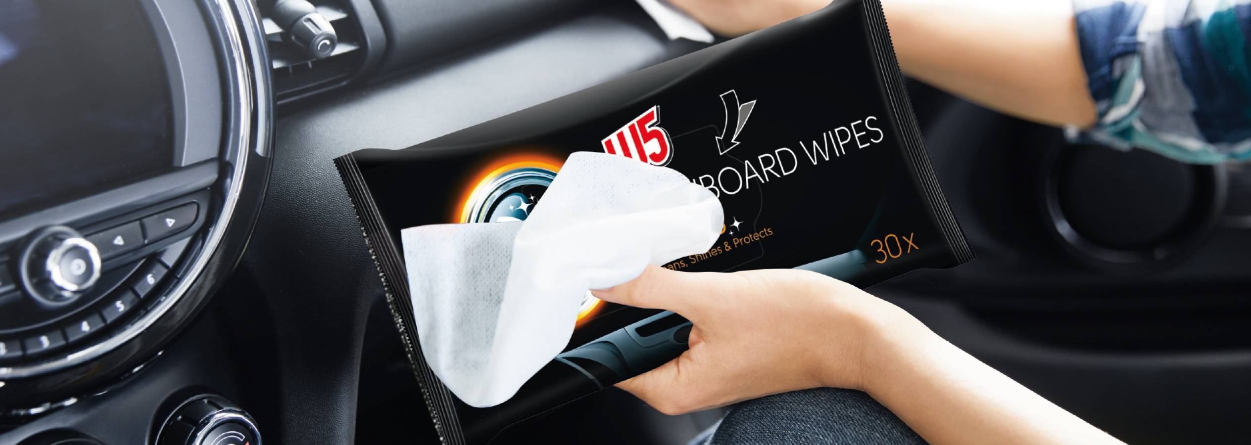 En person holder en pakke med 115 Dashboard Wipes i en bil.