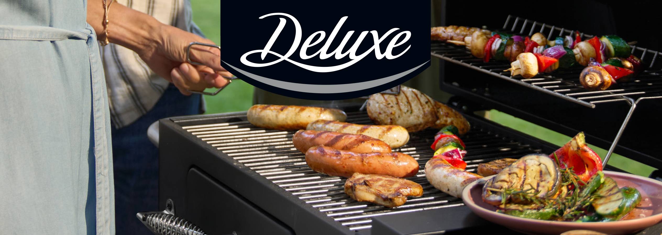 Deluxe grillfest med pølser, grøntsager og kød på en grill.