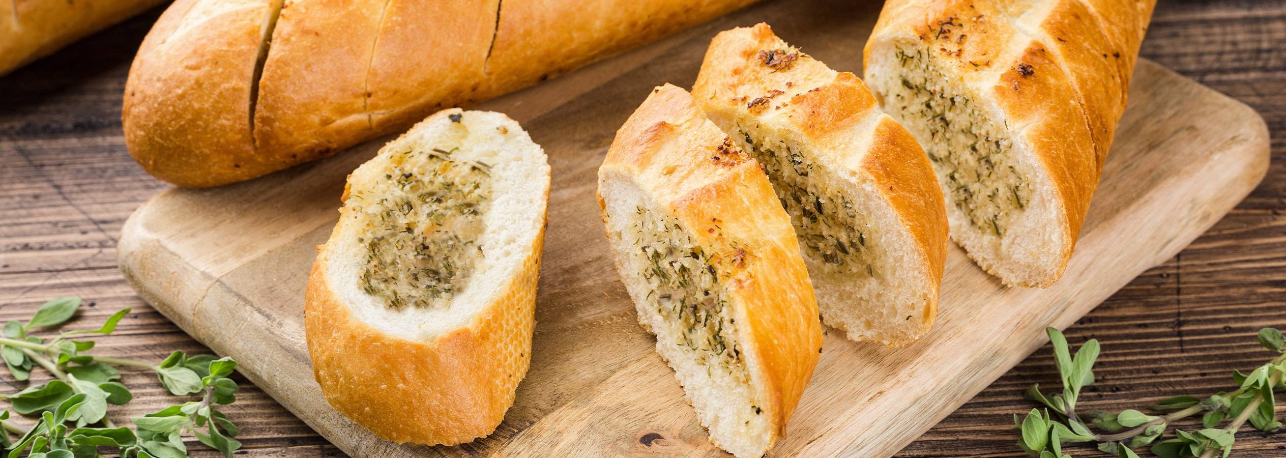 Friskbagt hvidløgsbrød skåret i skiver på et træbræt.