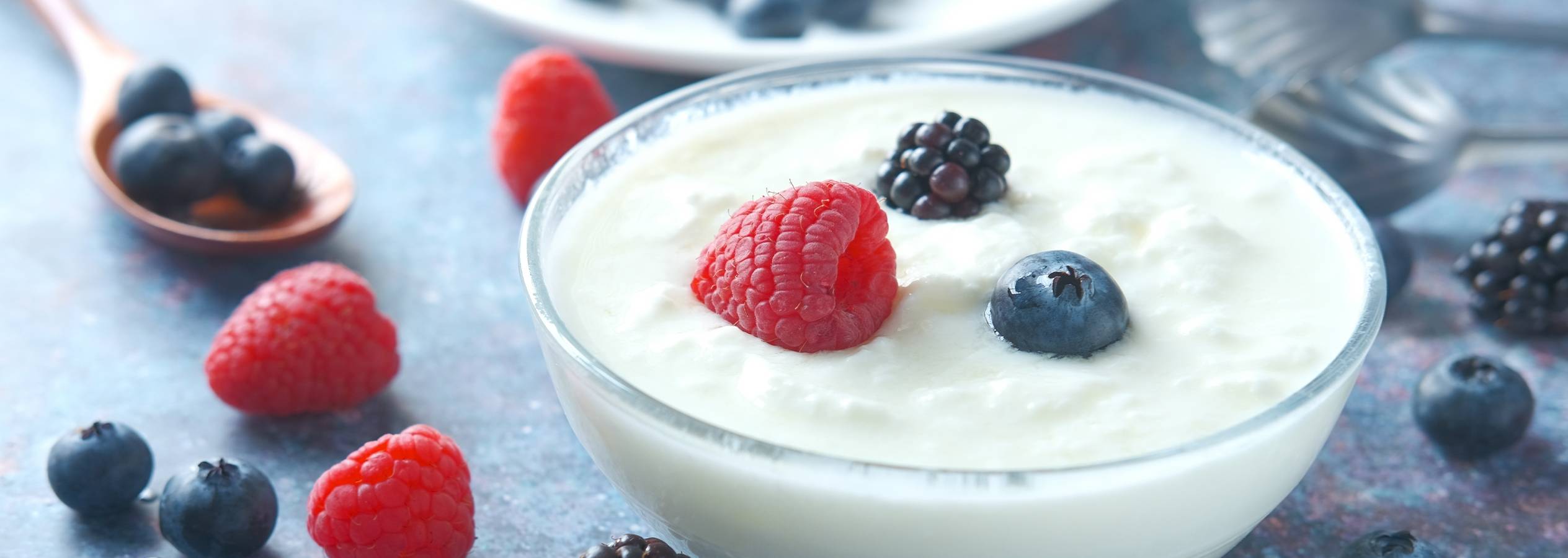 En skål med yoghurt toppet med hindbær, brombær og blåbær.