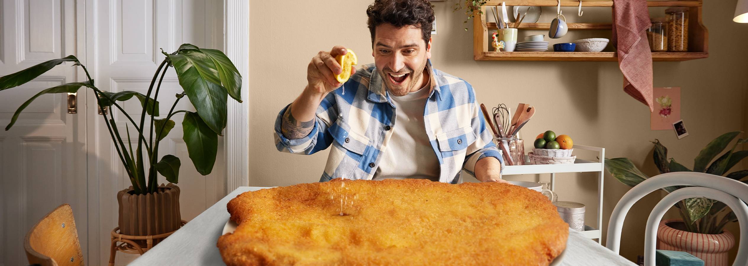 En mand sprøjter citron over en kæmpe schnitzel.