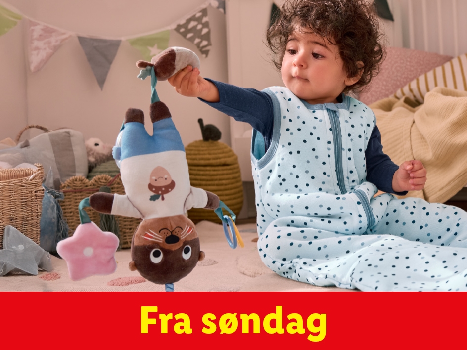 Baby i en baby sovepose leger med en sød otter-legetøj.