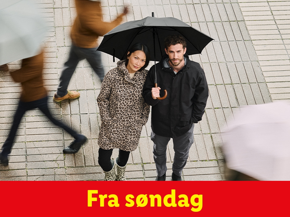 Et par med paraplyer og regntøj på en befærdet gade.