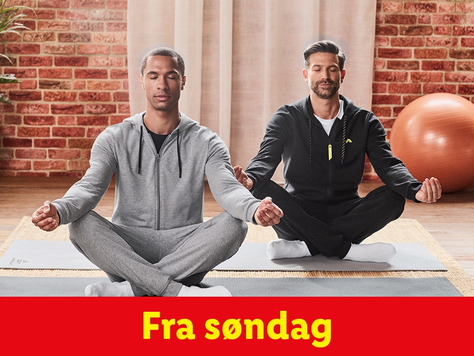 To mænd med lukkede øjne mediterer i træningsdragter på yogamåtter.