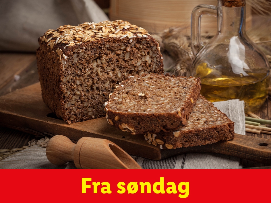 Rugbrød skåret i skiver på et træbræt, med en oliekrukke i baggrunden. Fra søndag.