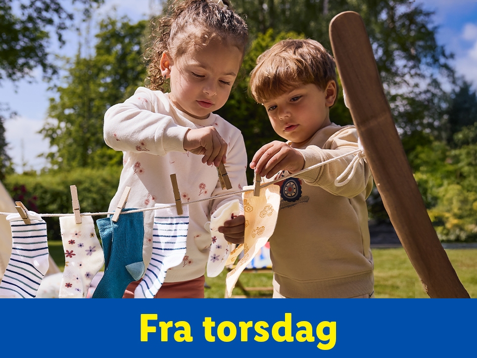 To børn hænger tøj op på en tørresnor i haven.