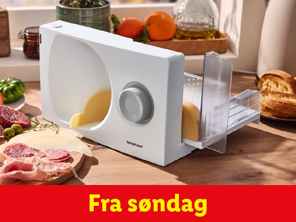 En Silvercrest pålægsmaskine skærer ost, med pålæg og brød på et træbord.