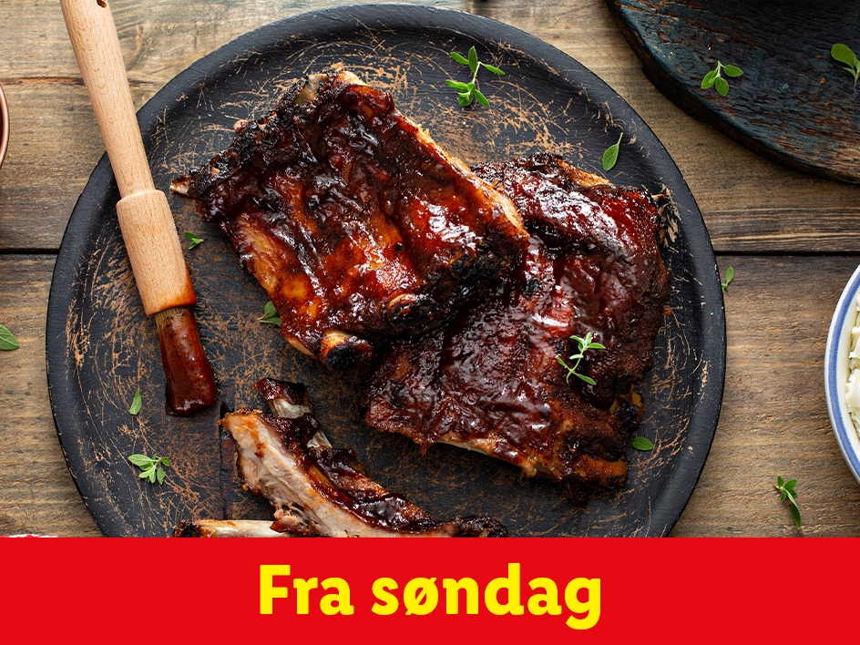 BBQ-ribbensteg serveret på en mørk tallerken med en pensel og krydderurter. Fra søndag.