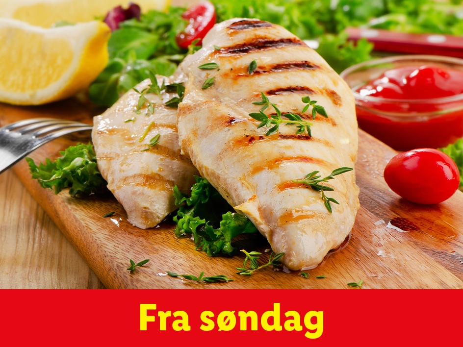 Grillet kyllingebryst med salat, citron og ketchup på et træskærebræt.