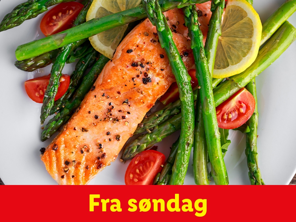 Laks med asparges, tomater og citron på en hvid tallerken.