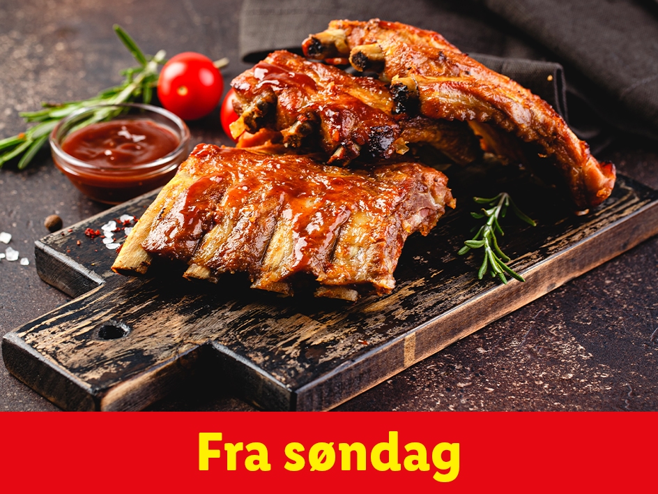 Grillede spareribs med sauce, rosmarin og tomater på et træskærebræt.
