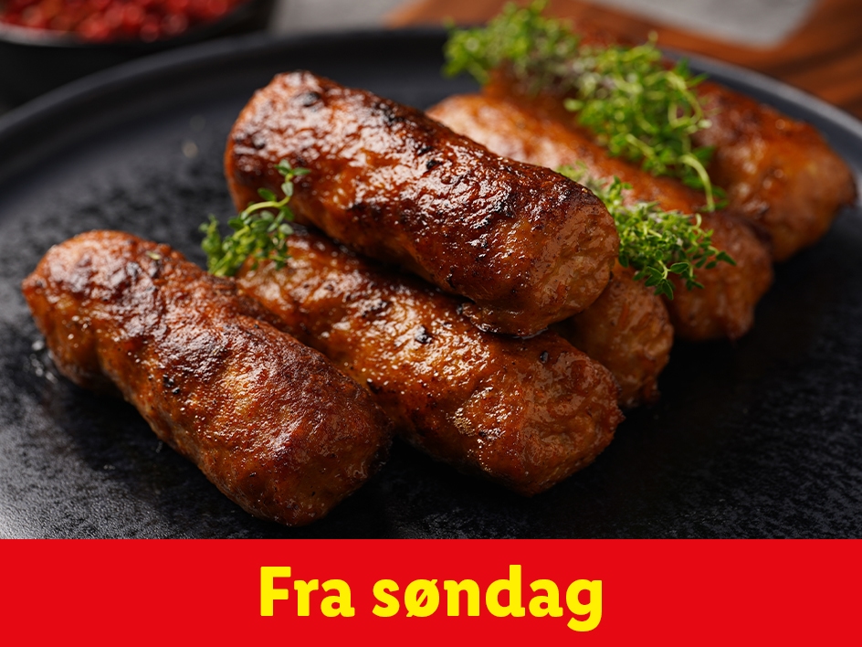 En tallerken med gyldenbrune pølser pyntet med friske krydderurter.