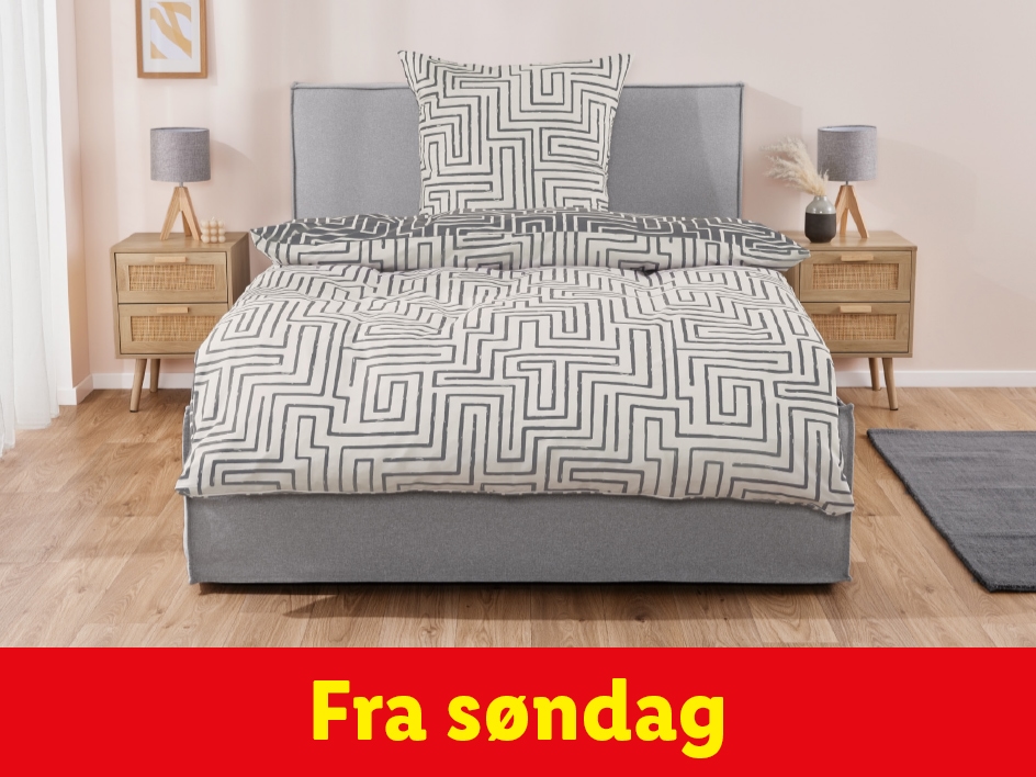 Seng med gråt sengetøj og mønster, to sengeborde med lamper.