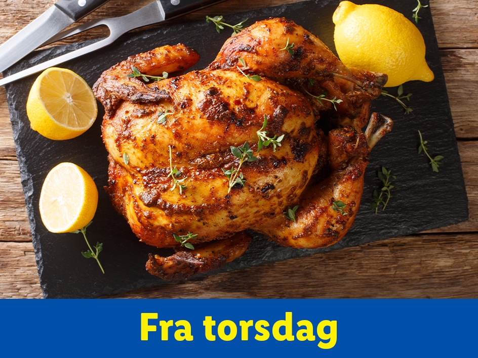 Helstegt kylling med citroner og krydderurter på et skærebræt.